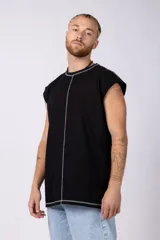 Musculosa oversize de algodón estilo sudadera, color crudo, con costuras visibles en contraste en color negro que recorren el centro verticalmente y enmarcan el cuello y el ruedo.