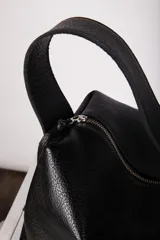 Cartera negra de cuero granulado, con cierre metálico y doble correa regulable y desmontable. Cuenta con un bolsillo interior con cierre y otro para el celular.