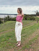 Pollera larga de lino color blanco, con diseño cruzado tipo pareo y cierre ajustable con hebilla redonda de madera en la cintura.