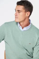 Suéter de tejido fino color azul marino, con cuello en V y manga larga. Presenta un pequeño logo bordado en el pecho.