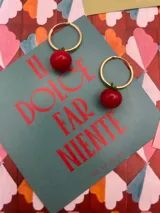 Par de aros dorados con dije colgante de cereza roja.