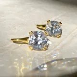 Par de aros dorados con circonia cúbica transparente de corte cushion, engarzada con cuatro garras.