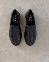Mocasines negros de estilo clásico con textura de cuero grabado tipo cocodrilo. Presentan una banda frontal característica y suela plana con borde definido.
