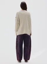 Buzo tejido de punto color beige, con cuello subido, diseño oversized y aberturas laterales en el ruedo.