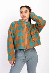 Campera corta de polar color beige con estampado de estrellas negras, cuello alto y cierre frontal.