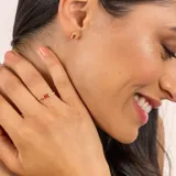 Anillo dorado con piedra central rectangular color borgoña y dos diamantes circulares a cada lado.