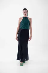 Vestido largo con cuello halter enteramente cubierto de lentejuelas, que combina un cuerpo superior en tono rosado y una falda larga en color negro.