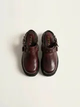 Zueco de cuero vacuno color bordó, con diseño de punta redondeada, detalle de tira con tachas metálicas y herrajes en tono oro viejo. Cuenta con un taco cuadrado de 4,5 cm y suela de cuero.