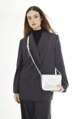 Bandolera compacta de cuero vacuno color gris con efecto gastado, solapa redondeada y correa ajustable.