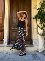 Falda larga negra con estampado floral blanco, de tela con spandex y elástico en la pretina.