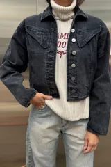 Campera de jean con efecto lavado ácido en color negro, de corte vintage, con costuras reforzadas en hilo color maíz y botones metálicos frontales.