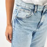Pantalón jean de corte globo y tiro alto, en tono azul claro con efecto lavado. Presenta diseño amplio de perneras curvas y costuras decorativas.