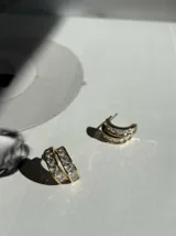 Par de aros tipo argolla dorados con incrustaciones de zirconias blancas. Cierre tipo mariposa y aguja de plata 925.
