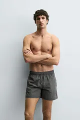 Bañador de hombre de largo medio, color celeste claro con rayas blancas horizontales. Presenta cintura elástica ajustable con cordón, bolsillos frontales y bolsillos traseros de plastrón. Incluye forro interior.