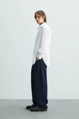 Camisa de corte slim fit con textura, cuello italiano y manga larga con puños abotonados. Presenta cierre frontal con botones.