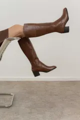 Bota de cuero negra con caña alta, taco cuadrado y punta redondeada.