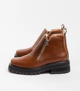 Bota de cuero vacuno color marrón, con interior forrado en corderito natural. Tiene suela de goma artesanal, punta cuadrada, cierre YKK en ambos lados y caña de 11cm.