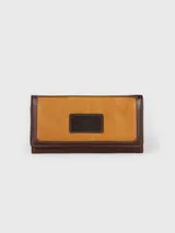 Billetera de cuero combinada en tonos tostado y marrón oscuro, con solapa frontal y parche con logo grabado.