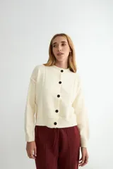 Cardigan de punto color marrón chocolate, con cuello redondo, cierre frontal de botones y diseño de costuras verticales visibles. Presenta puños y ruedo acanalados.