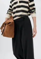 Pantalón de vestir de corte recto y tiro alto, con cierre frontal y trabillas para cinturón. Presenta pinzas en la parte delantera que aportan estructura a la prenda.