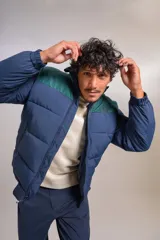 Campera puffer con diseño bicolor, cuerpo en azul marino y canesú superior en verde oscuro. Presenta cuello alto, cierre frontal completo y puños elásticos.