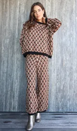 Pantalon de punto con diseño geométrico de arcos en tonos marrones, negros y beige. Presenta corte recto y holgado con cintura elástica.