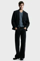 Blazer de botonadura sencilla con solapas de muesca, cierre de dos botones y abertura doble trasera. Presenta un diseño a rayas finas, bolsillo superior, bolsillos delanteros con solapa y botones decorativos en los puños. Cuenta con forro interior y dos bolsillos internos.