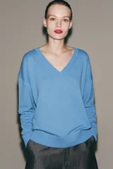 Sweater de punto color celeste, con escote en V y mangas largas con hombros caídos. Presenta terminaciones en rib en cuello, puños y ruedo.