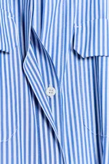 Vestido midi de popelín de algodón, con cuello solapa, manga corta con puño y bolsillos delanteros con solapa. Presenta un cinturón a tono anudado en la cintura y cierre frontal con botones.