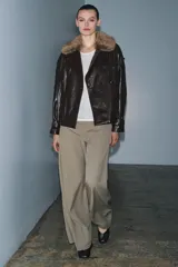 Chaqueta de efecto cuero con acabado brillante, cuello de solapa con aplicación de pelo sintético extraíble, cierre frontal cruzado con botones, mangas largas con puños ajustables y bajo elástico. Cuenta con forro interior acolchado.