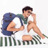Bolso mochila de tela canvas color azul, con detalles en cuero marrón. Cuenta con apertura vertical, correas ajustables para usar como mochila, asas superiores y correa de hombro extraíble. Incluye compartimentos internos y bolsillos de seguridad con cierre.