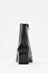 Bota de cuero color negro con diseño estilo western, punta fina y tacón cubano. Presenta detalles de bordado y textura de cocodrilo en la parte delantera.