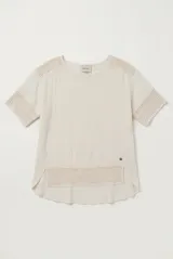 Blusa color blanco, de corte holgado y mangas tres cuartos, con detalles de encaje y bordados en las mangas y en el ruedo.