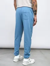 Pantalón de jogging gris de felpa sin friza, con cintura elástica ajustable con cordón y logo de Umbro estampado en blanco en el muslo izquierdo.
