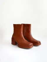 Bota de caña media color óxido, confeccionada en cuero, con plataforma y taco cuadrado texturizado, punta cuadrada y cierre lateral.