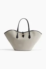 Cartera tipo shopper con diseño de borde superior ondulado y estructura sesgada. Presenta asas finas de cuero negro y un cierre central con detalle metálico dorado. El cuerpo de la cartera posee un patrón geométrico sutil en tonos beige y gris.