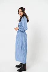 Vestido largo a rayas verticales azules y blancas, con manga globo y diseño de nido de abeja con hilo elástico hasta la cintura. Cuello alto fruncido y falda amplia con caída fluida.