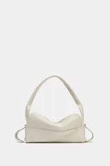 Bolso alargado de piel color blanco hueso, con asa de hombro y cierre de cremallera.