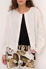 Chaqueta de lino color beige, de manga larga, con cuello redondo y cierre frontal de botones a presión con solapa.