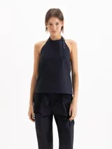 Top Lucille de silueta evasé, calce holgado y corte cropped, confeccionado en poplín Milano de algodón Pima. Cuenta con escote halter de sisa profunda, bretel regulable con ojalillos de níquel que envuelve el cuello, pinzas de entalle y espalda abierta.