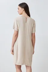 Vestido corto color beige melange, de lino, con cuello en V y mangas cortas. Presenta pespuntes verticales en contraste.