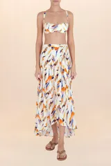 Falda pareo larga de caída fluida, con estampado abstracto en tonos naranja, azul y rosado sobre fondo blanco. Diseño cruzado con amarre lateral y corte asimétrico con volado.