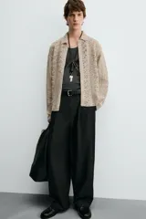 Sobrecamisa de hombre color beige, confeccionada en tejido de crochet con estructura abierta, cuello solapa, manga larga y cierre frontal de botones.