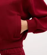 Campera deportiva tipo bomber de color bordó, con cierre frontal por cremallera, cuello redondo, mangas largas con puños elásticos y bolsillos laterales. Presenta un detalle de lettering bordado en el pecho.