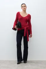 Sweater de punto acanalado color rojo, con escote en V, mangas largas acampanadas y lazo ajustable en la cintura.