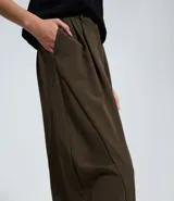Pantalón sastre de corte barrel, con diseño de piernas anchas y volumen estructurado en los laterales. Presenta pliegues frontales, cintura con elástico en la parte posterior y acabado refinado.