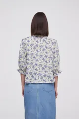 Blusa de viscosa con estampado floral, cuello a la base con detalle de volados, cierre frontal con botones y mangas tres cuartos abullonadas con puños elásticos.