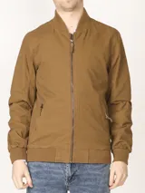 Campera tipo bomber color marrón, 100% algodón, con cuello, puños y cintura tejidos al tono. Cierre frontal metálico y bolsillos laterales con cierre.