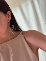 Aros colgantes plateados con forma de flor abstracta.