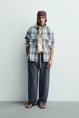 Camisa de algodón de corte relajado, con cuello solapa, manga larga terminada en puño con botón y dos bolsillos de plastrón con solapa en el pecho. Presenta un estampado de cuadros en tonos azules, grises y blancos, y cierre frontal de botonadura.